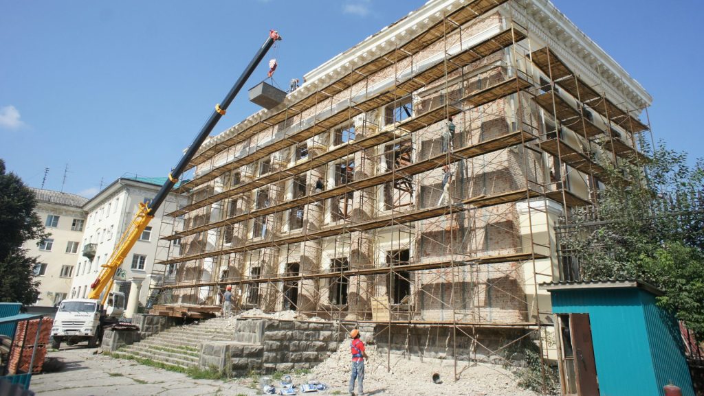 Building undergoing renovation with scaffolding and crane.