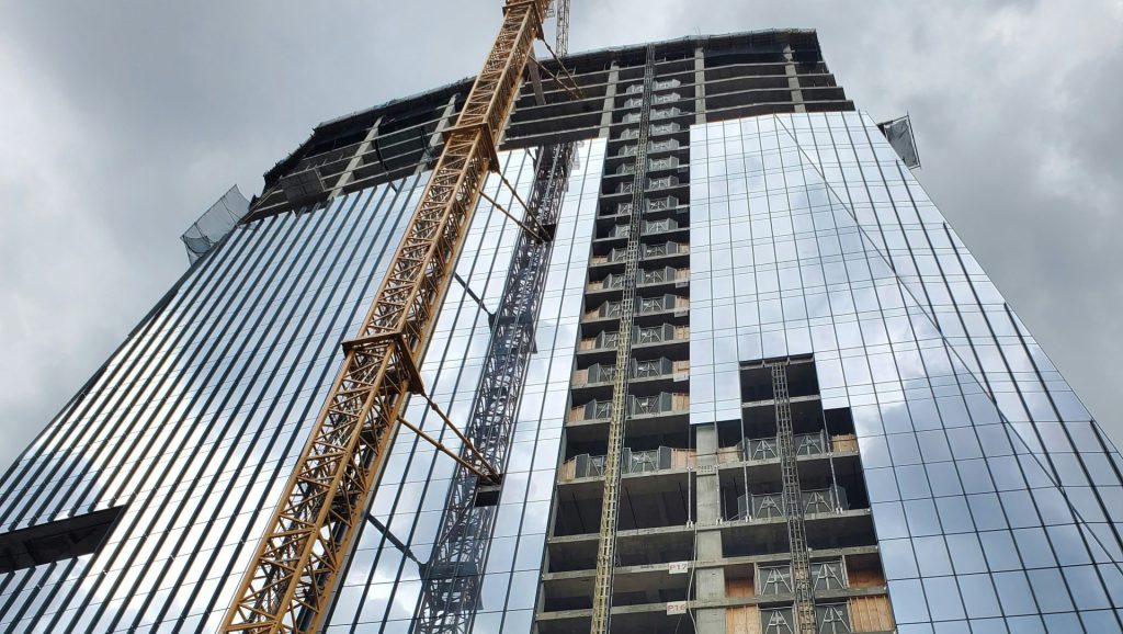 Skyscraper under construction with crane against cloudy sky